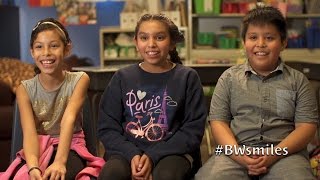 Three kids smiling and talking to the camera