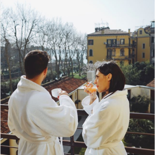 Couple in bathrobes sipping coffee and juice enjoying the view