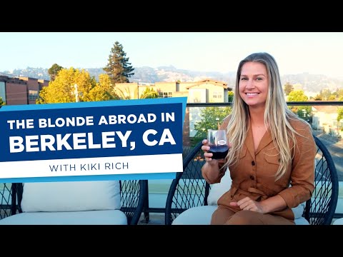 Blonde girl sitting at a rooftop table drinking red wine.