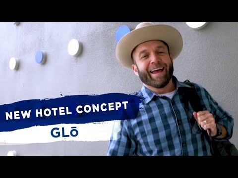 Man in blue flannel shirt with beard and hat standing in hotel lobby