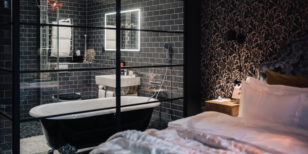 WorldHotels Crafted guestroom with a bed in the foreground, bathtub in the background