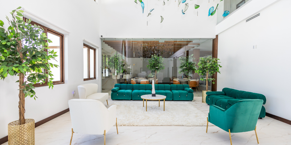 Bright white upscale hotel lobby with bright green furniture and art hanging from the ceiling