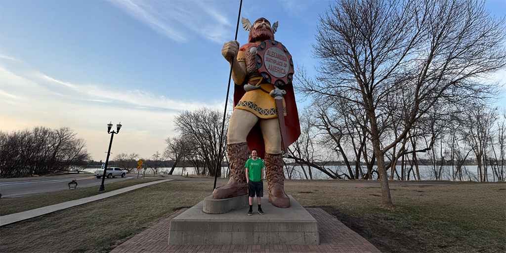 Man standing at the base of a tall nordic statue
