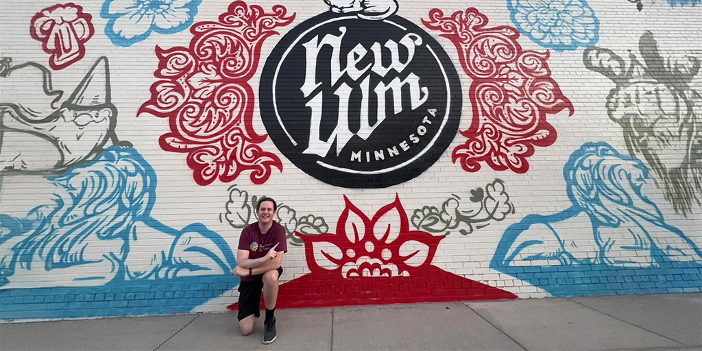 Man kneeling down in front of a red and blue mural