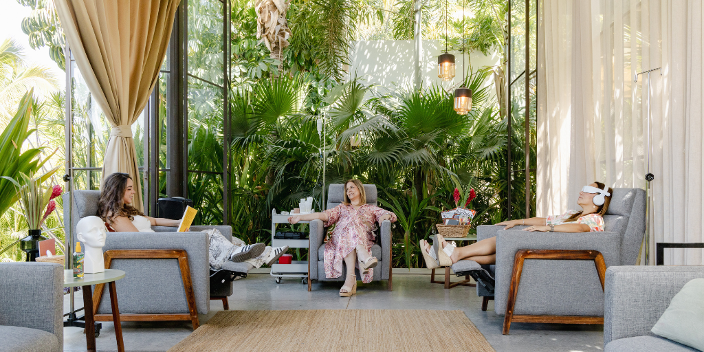 women sitting in a lobby with IVs attached to their arms