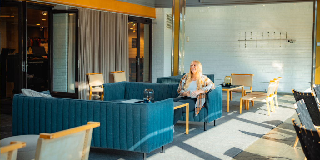 a woman sits in a colorful and comforting hotel lobby with bright blue chairs