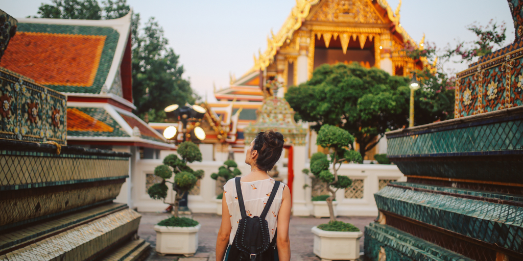 Solo female traveler wearing a backpack walks through Thailand